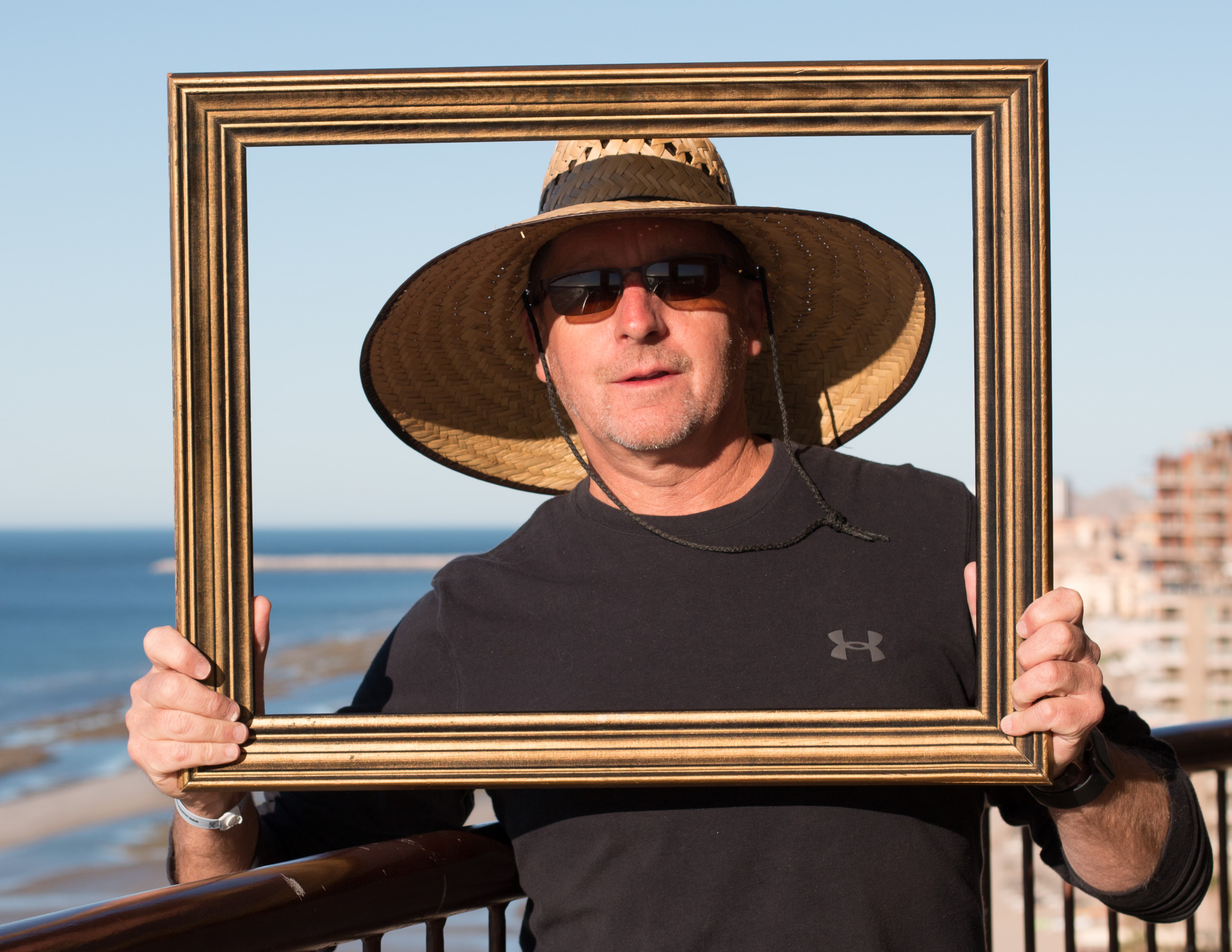 Person holding a picture frame outdoors in a public setting