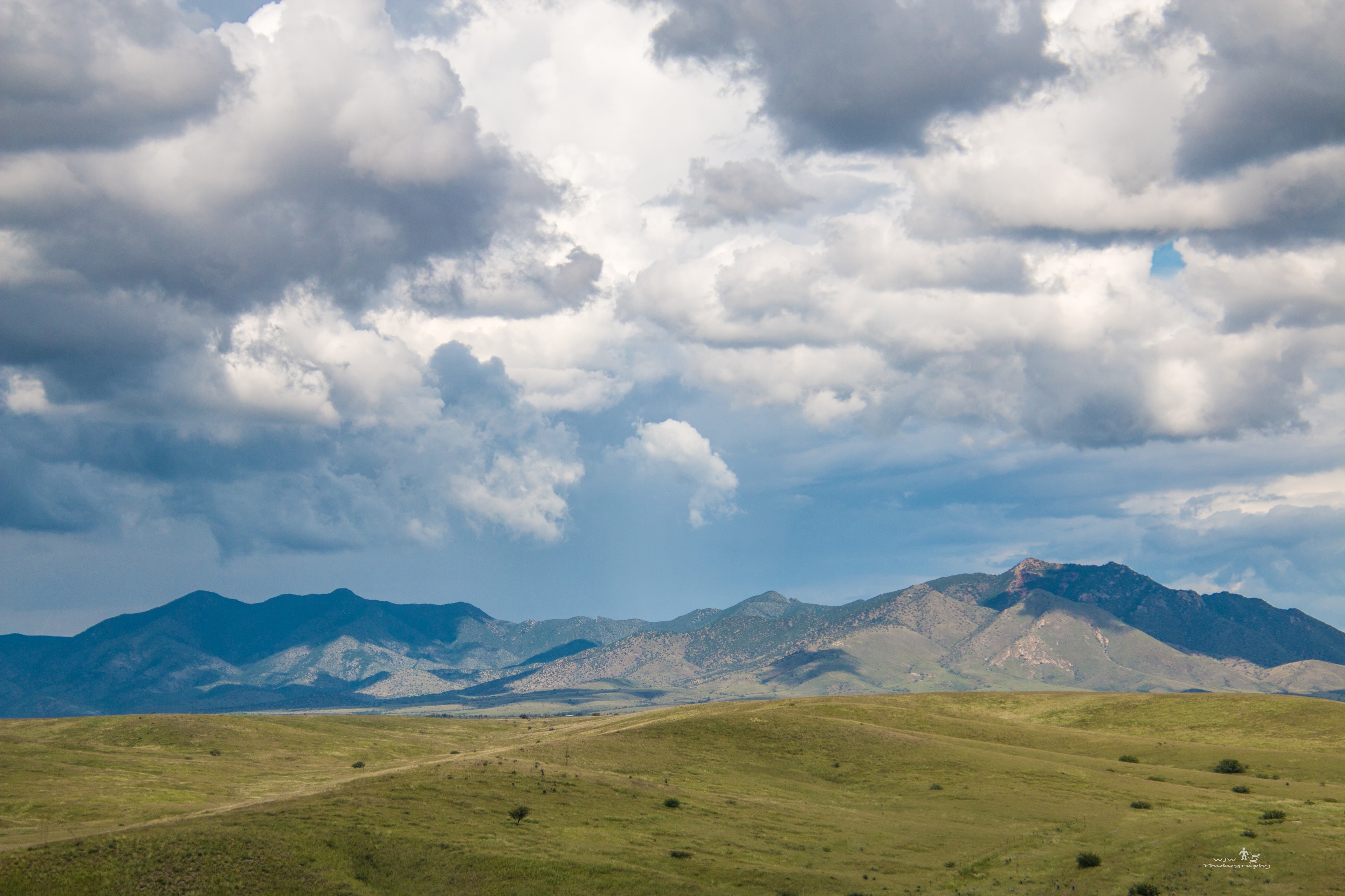 Mountain range with vast grassland under cloudy sky