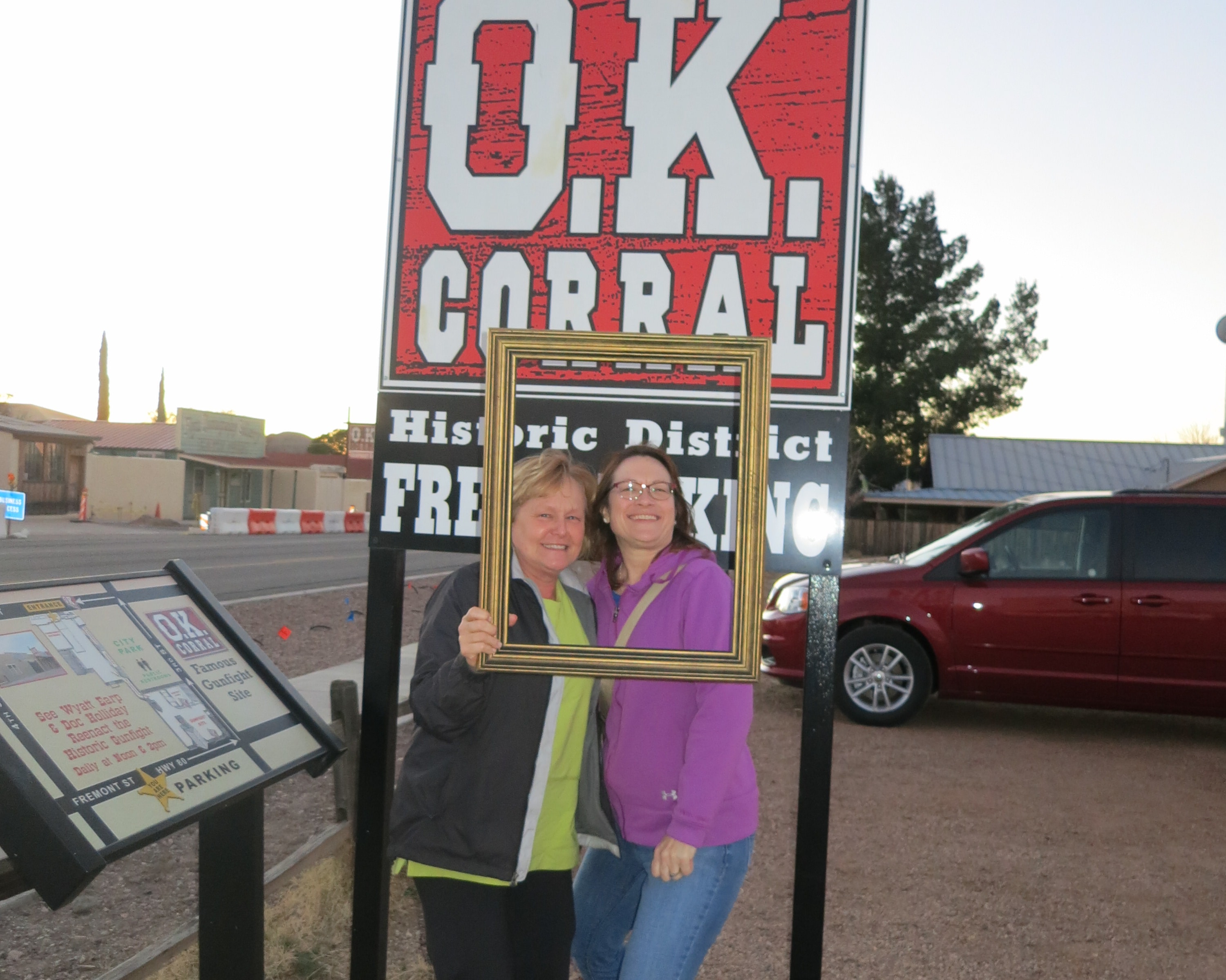 Two women holding a gold picture frame in front of the O.K. Corral sign in Tombstone