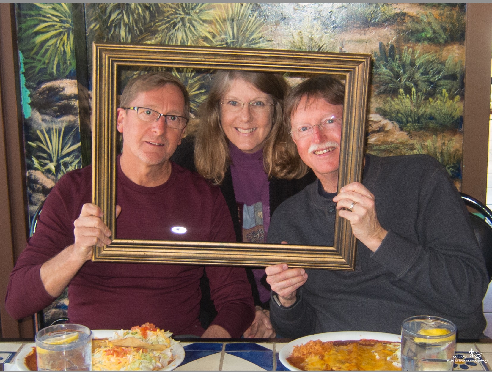 Group of people holding a gold picture frame together